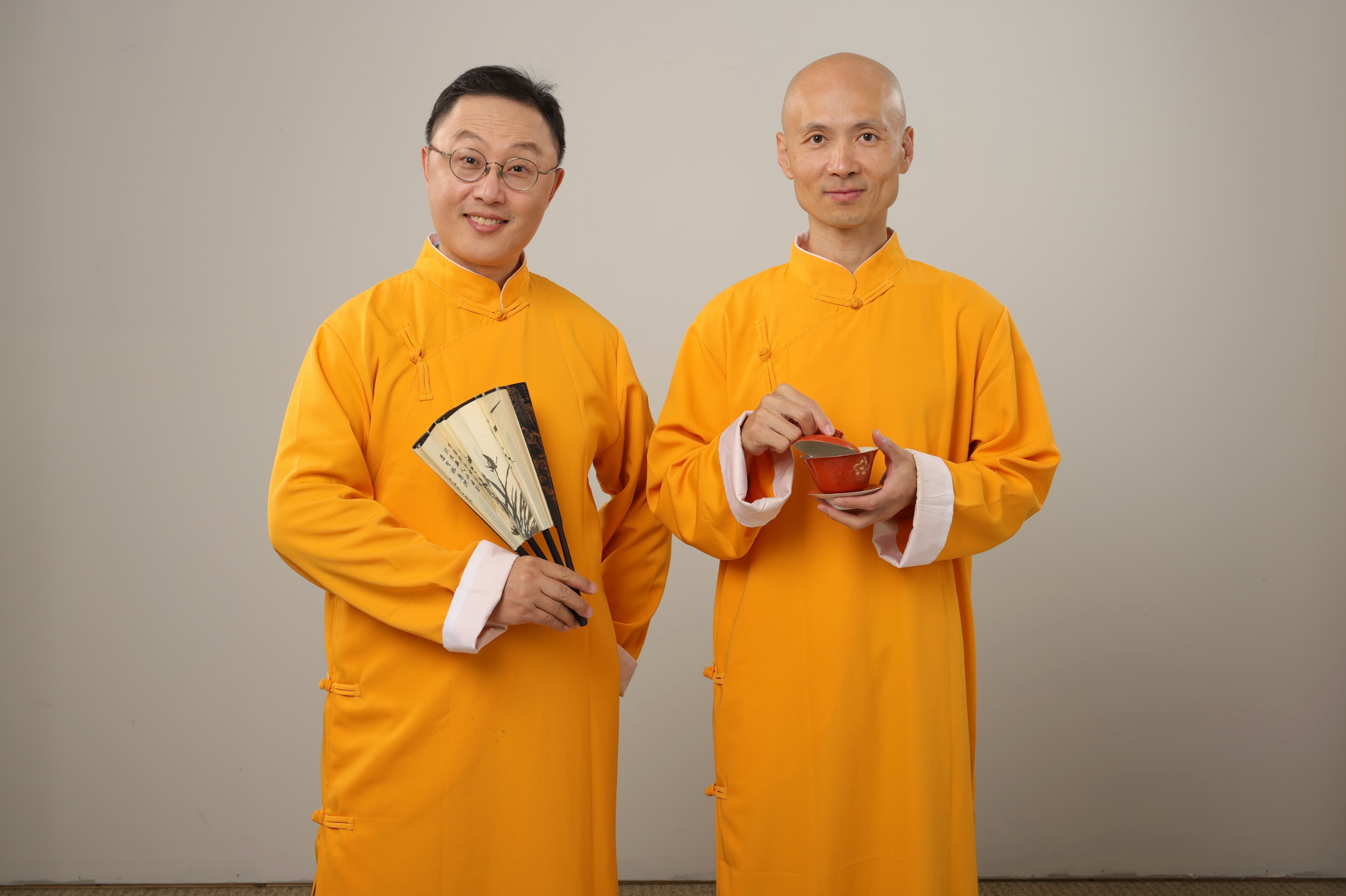 老北京茶館兩位主持人身穿金黃色長衫，一位持扇，一位捧茶